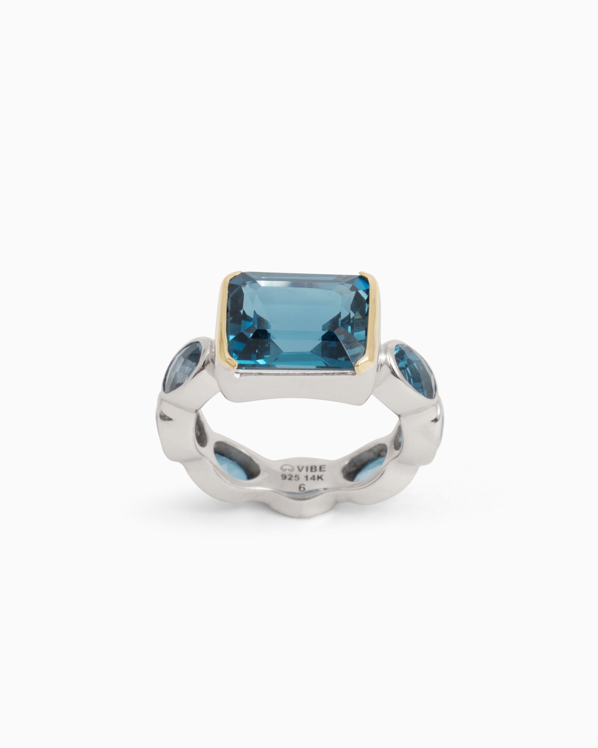 A sterling silver ring with a central square London blue topaz stone and smaller oval London blue topaz stones around the band, featuring a 14K gold accent around the center stone.